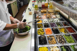 HACCP hero image close up picture of a chef preparing a stainless steel bowl full of assorted salad with salad ingredients
